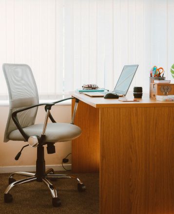 A tranquil modern home office featuring a wooden desk, ergonomic chair, and soft natural light.