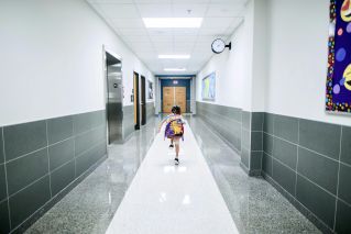 A child runs through a bright school hallway, emphasizing modern architecture and energy.